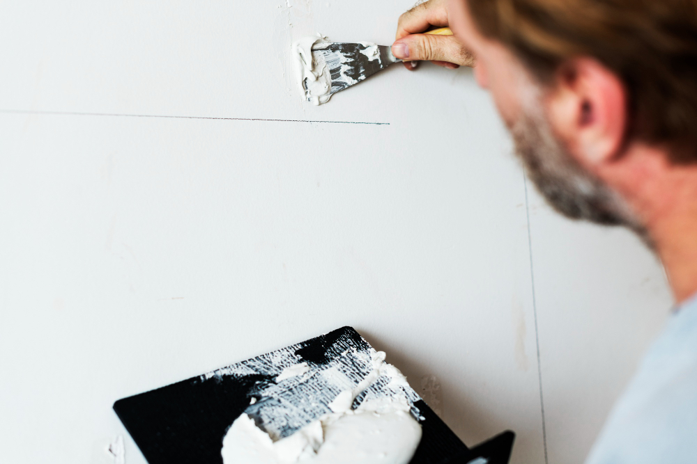 Nahaufnahme eines Handwerkers, der eine Wand perfekt glatt spachtelt